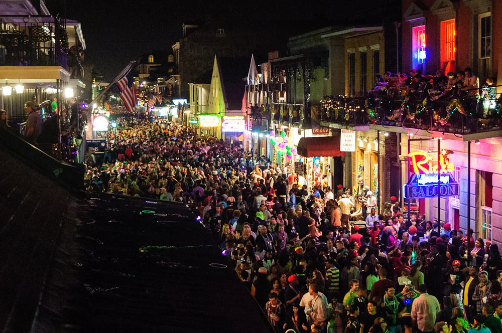 A packed nightlife street seen from a balcony after dark